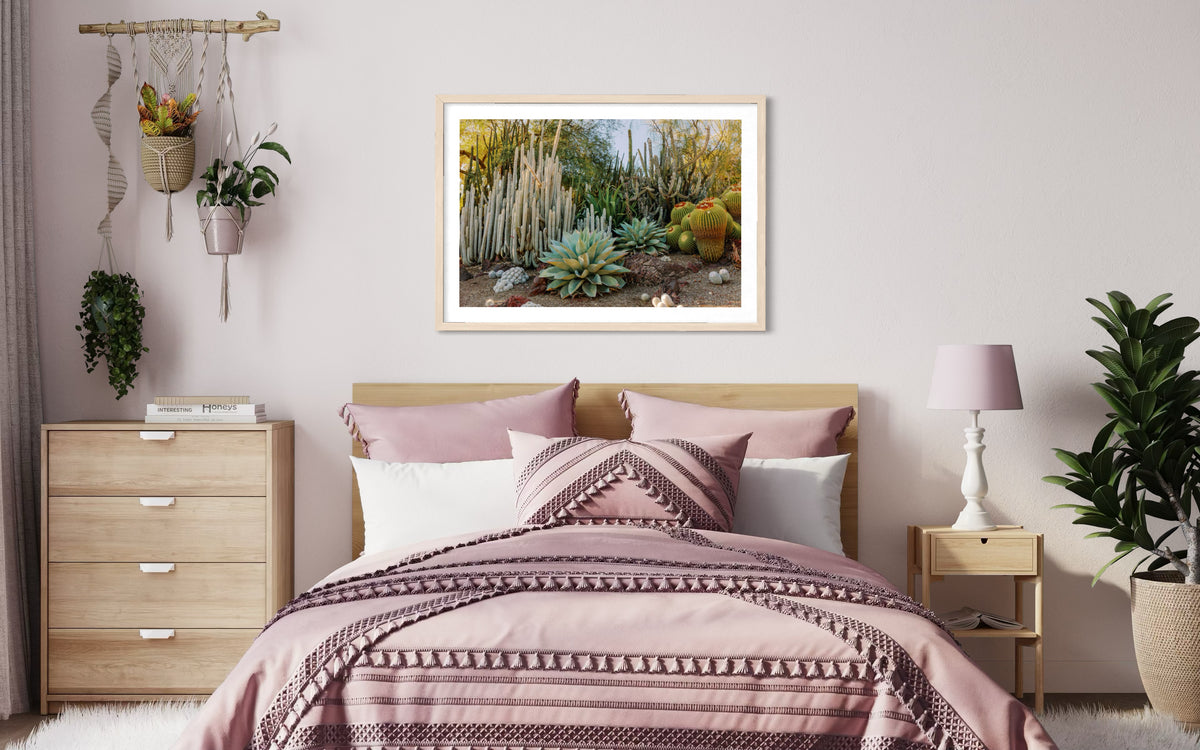 Bedroom with pink bedding, plants, natural decor, and Cactus Garden I photo above the bed in soft lighting.