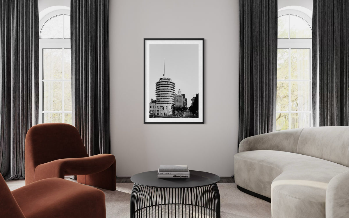 Two chairs and round coffee table in LA living room, Capitol Records Building photo displayed between windows.
