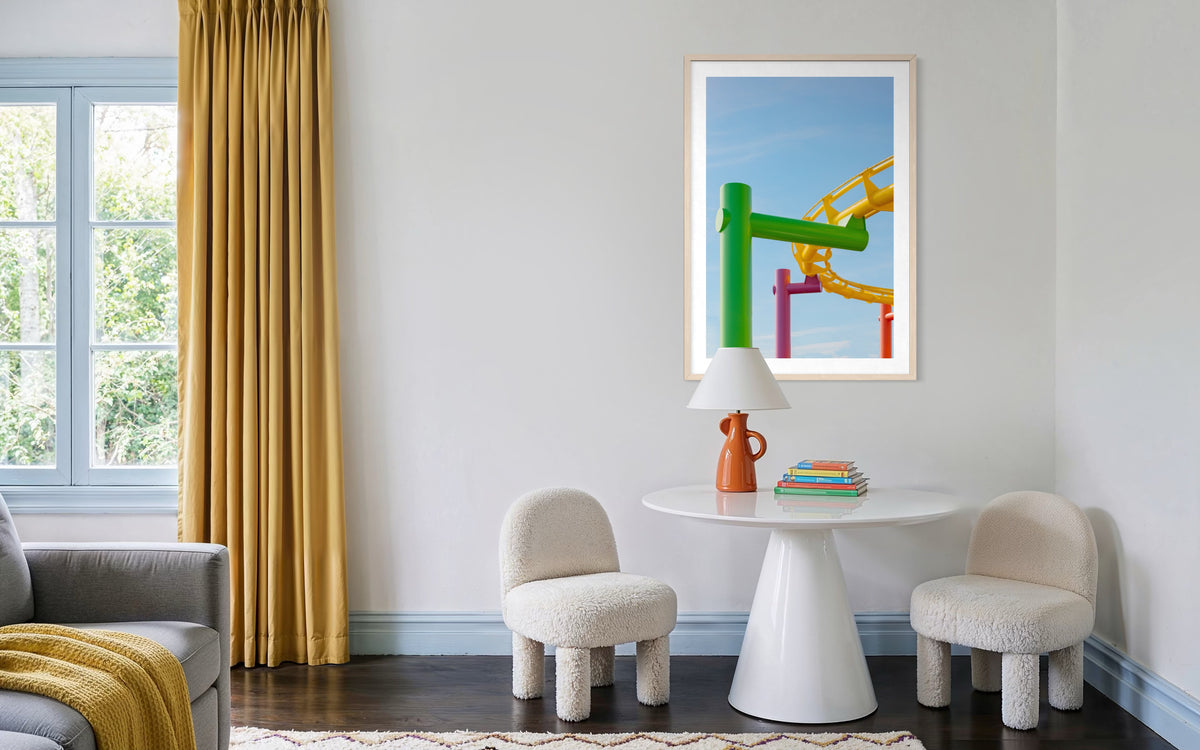 Two soft chairs and a round table with colorful coasters in a cozy room with yellow curtains.
