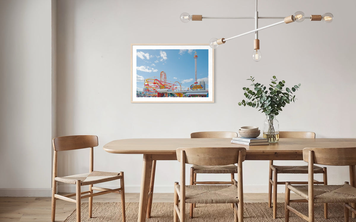 Dining room with wood table, chairs, plant, and “Coney Island Luna Games” photo on the wall.