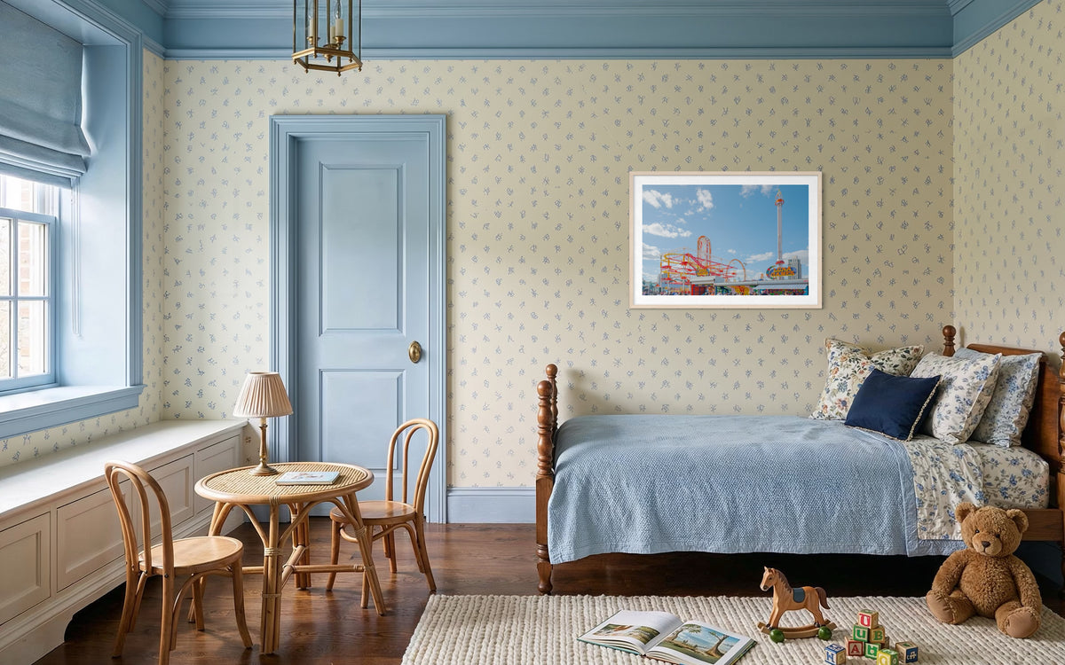 Wooden bed and toy table in a child’s room, with “Coney Island Luna Games” art above the bed.