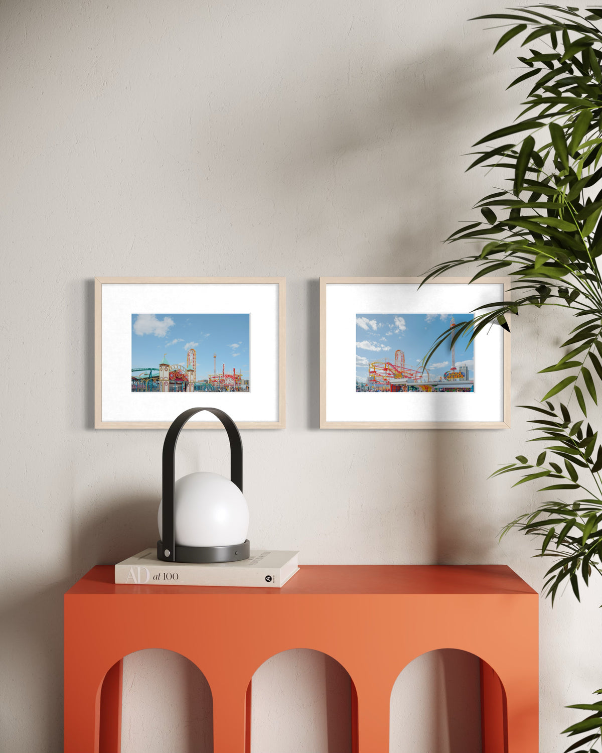 Red console with lamp, books, photos, plant, and Coney Island art against a pale wall in a Brooklyn apartment.