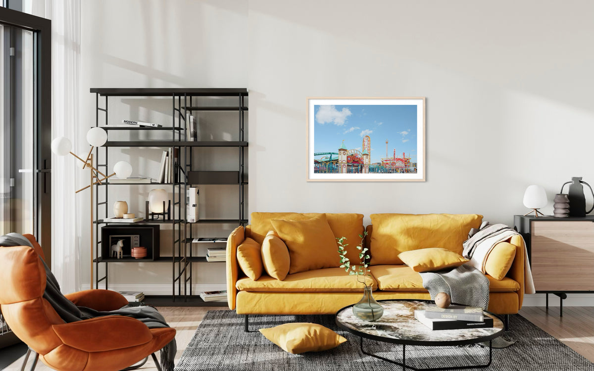 Yellow sofa and orange chair in a living room with bookshelves, Coney Island Thunderbolt art on the wall.