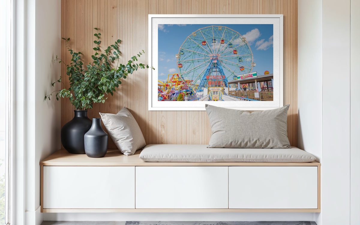 Bench with gray cushion, three vases, and framed photo of the Coney Island Wonder Wheel on a wood-paneled wall.