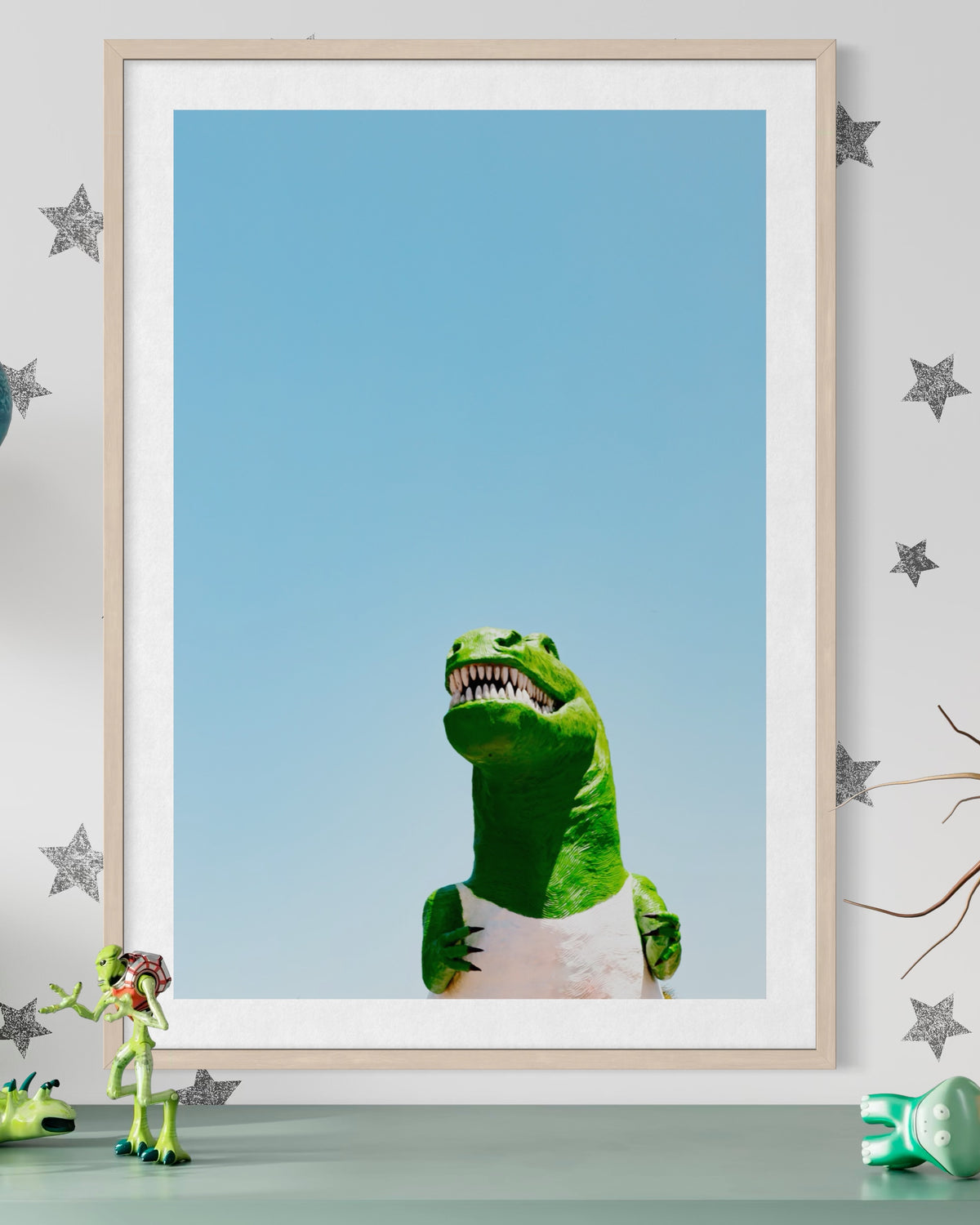 Dino, a green toy dinosaur, sits under the California sky with other toy dinosaurs and star stickers nearby.