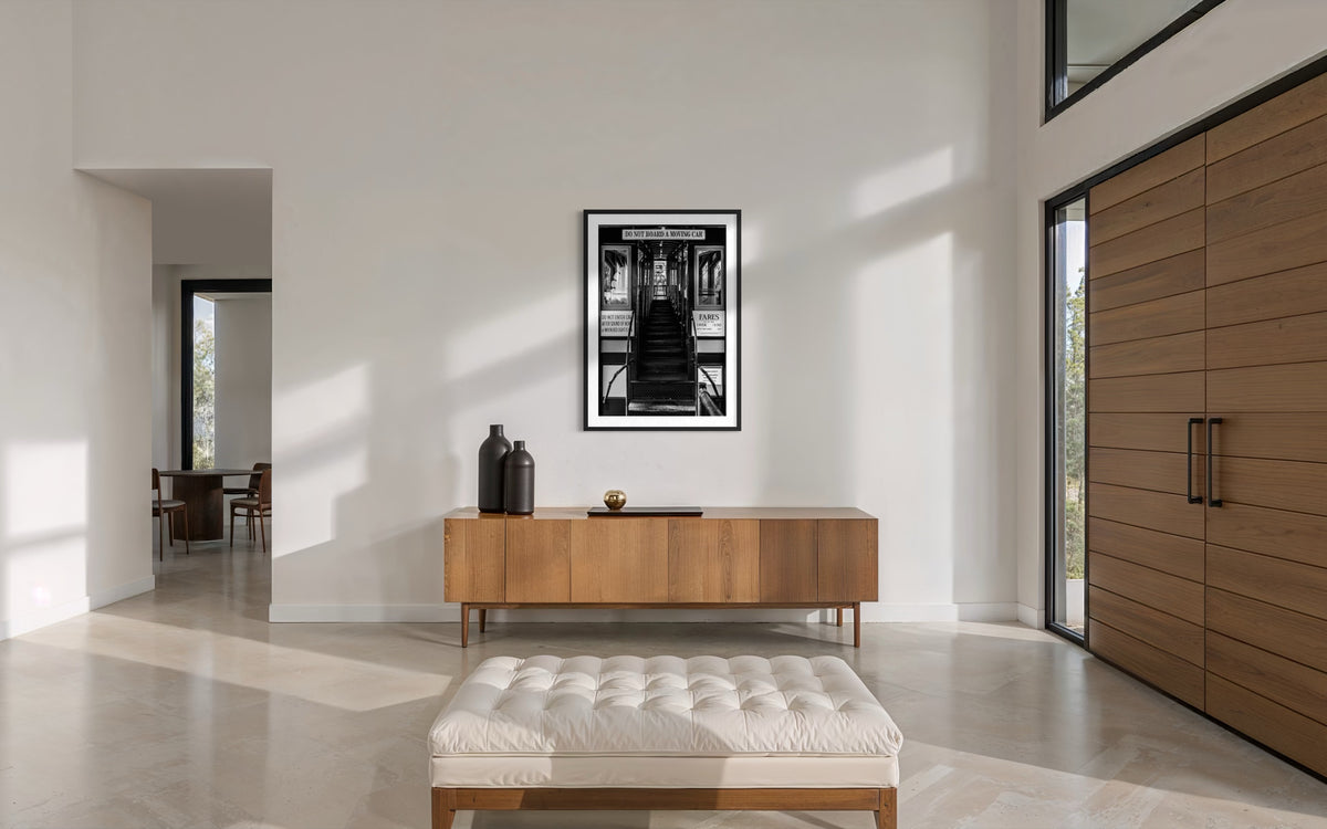 Wooden furniture and tufted bench beneath a “DTLA Funicular Passage” print on a white wall.
