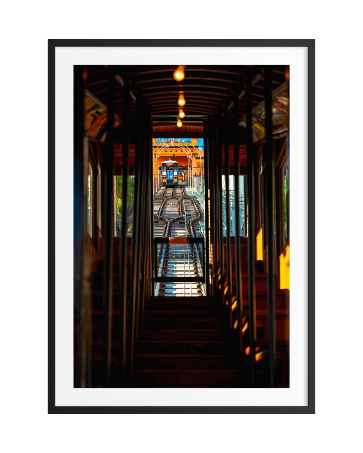 DTLA’s Angels Flight funicular climbs steep tracks toward a downtown Los Angeles station, interior lit by hanging lights.