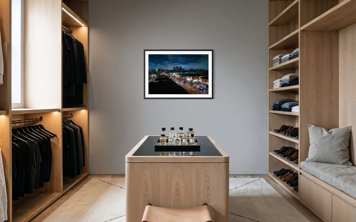 Walk-in closet with neatly arranged clothes and shelves, “DTLA Nights” cityscape art of Los Angeles on the wall.