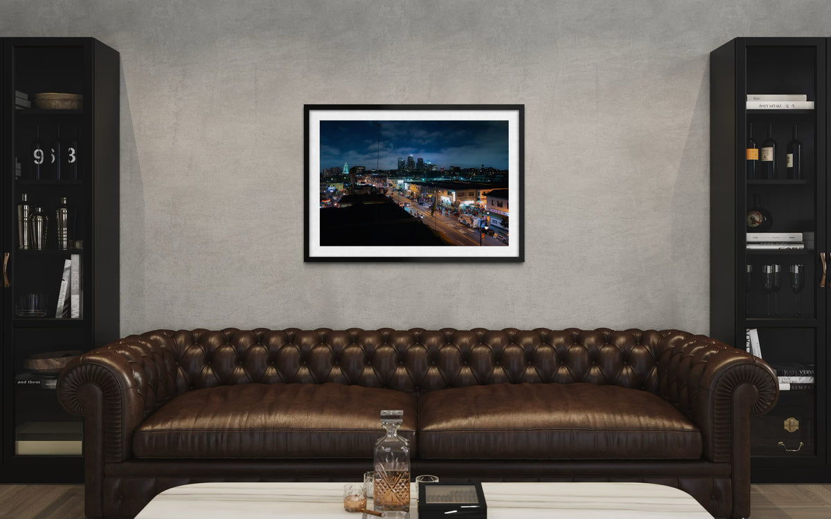 Brown leather sofa and black shelves in a modern gray living room with DTLA Nights cityscape artwork on the wall.