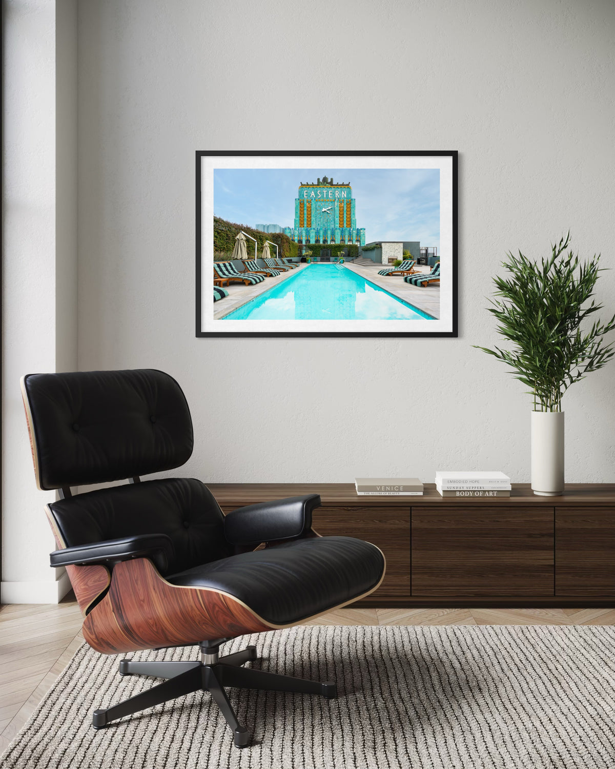 Black chair, wood console, and plant in a lounge, with Eastern Columbia Building print on the wall in Los Angeles.