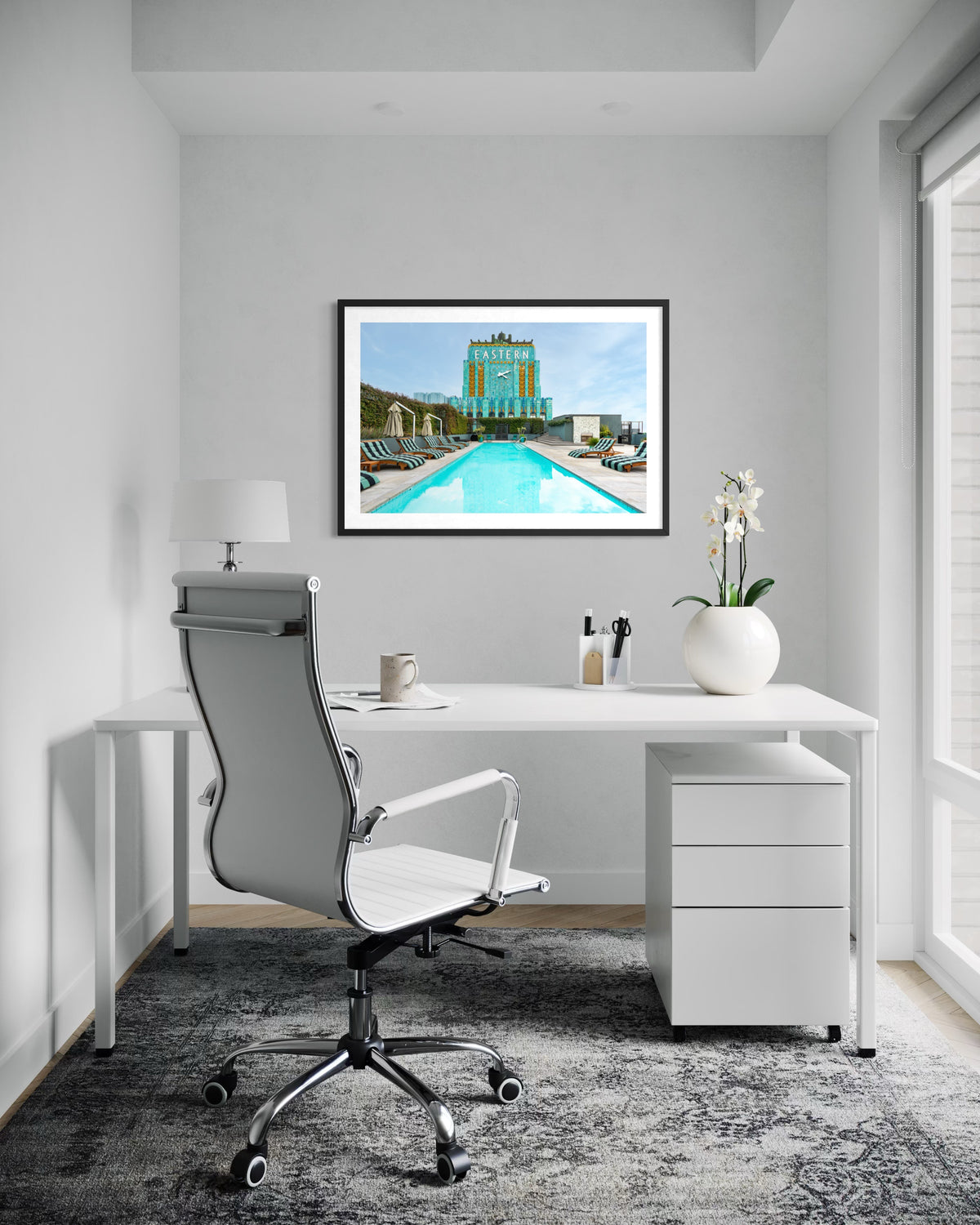 Framed photo of Los Angeles’ Eastern Columbia Building hangs above a white desk with orchid and chair.