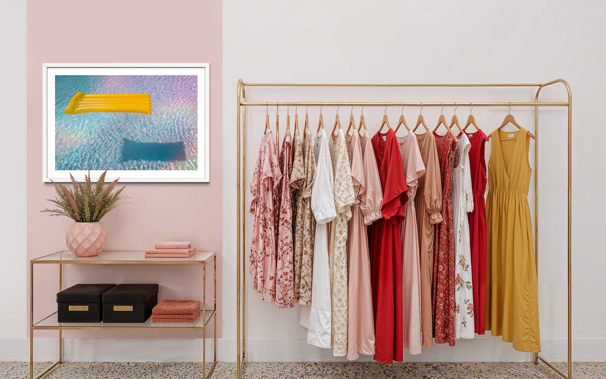 Gold clothing rack with colorful dresses, shelf decor, and “Floating Through Summer” wall art from Refractions Collection.