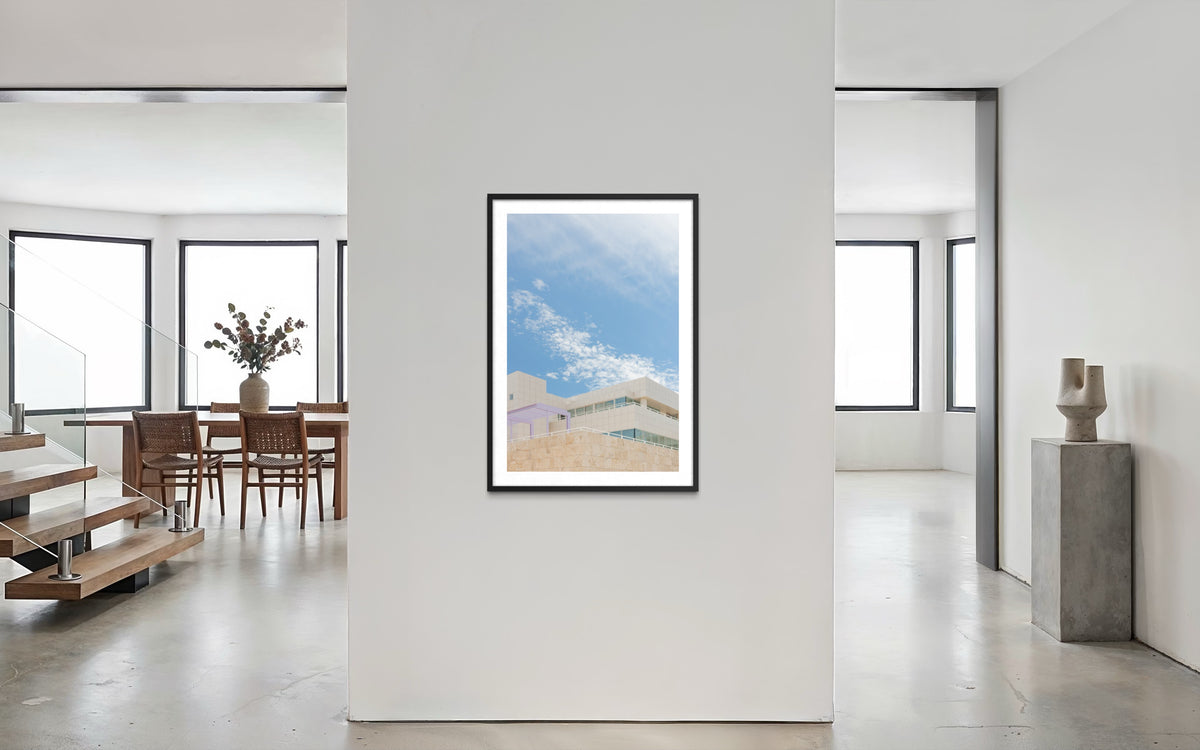 Framed Getty Center II print on white wall in bright room with large windows and travertine floors, Los Angeles.