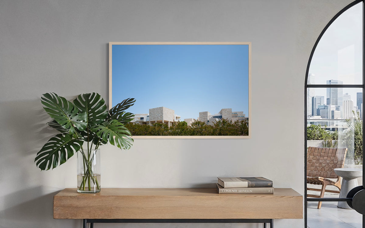 Framed print of the Getty Center, Los Angeles, displayed above a wood table with a leafy plant.