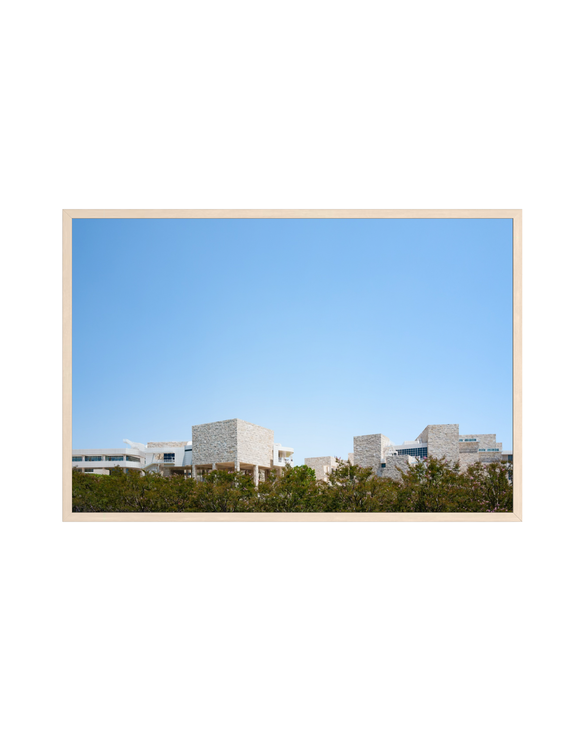 Travertine buildings of the Getty Center, Los Angeles, rise behind green trees and a light wood frame.