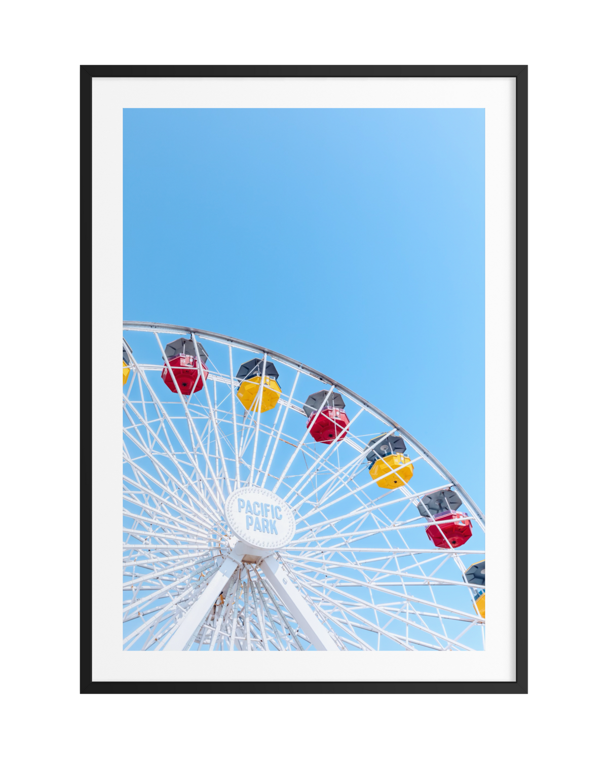 Red and yellow Ferris wheel at Pacific Park, Santa Monica, set against a bright summer sky.
