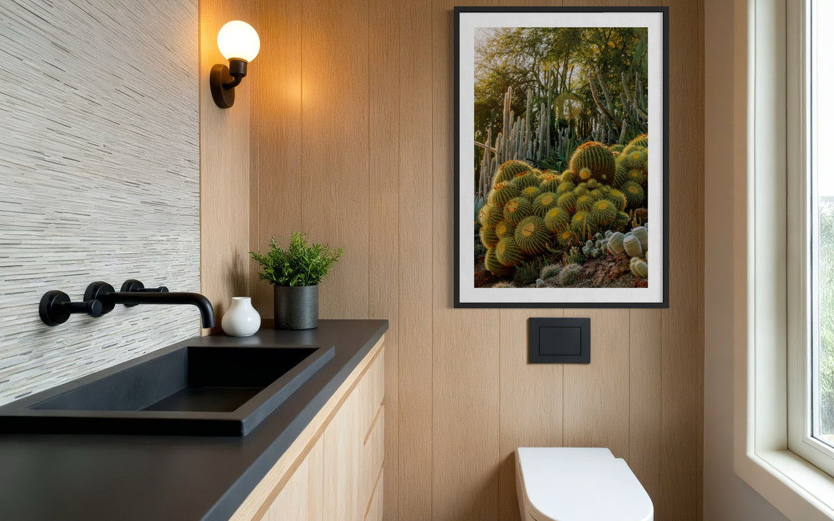 Wood-accented bathroom with black sink, potted plant, and Golden Barrel Cactus wall art in soft natural light.