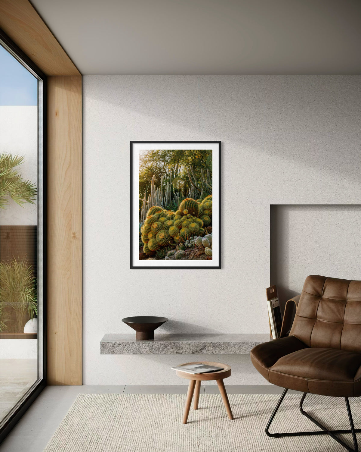 Framed Golden Barrel Cactus photo on a white wall above a leather chair and floating shelf in a living room.