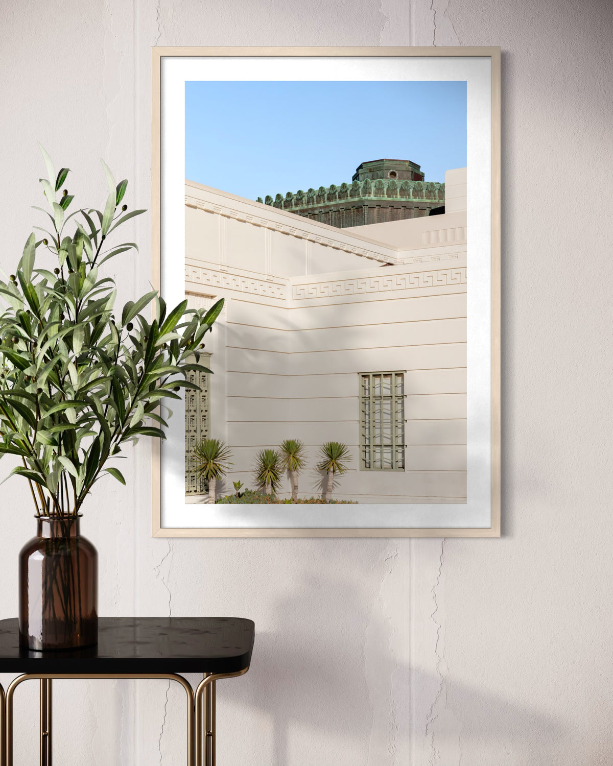 Framed Griffith Observatory Moment print displayed above a table with a green plant in a brown vase.