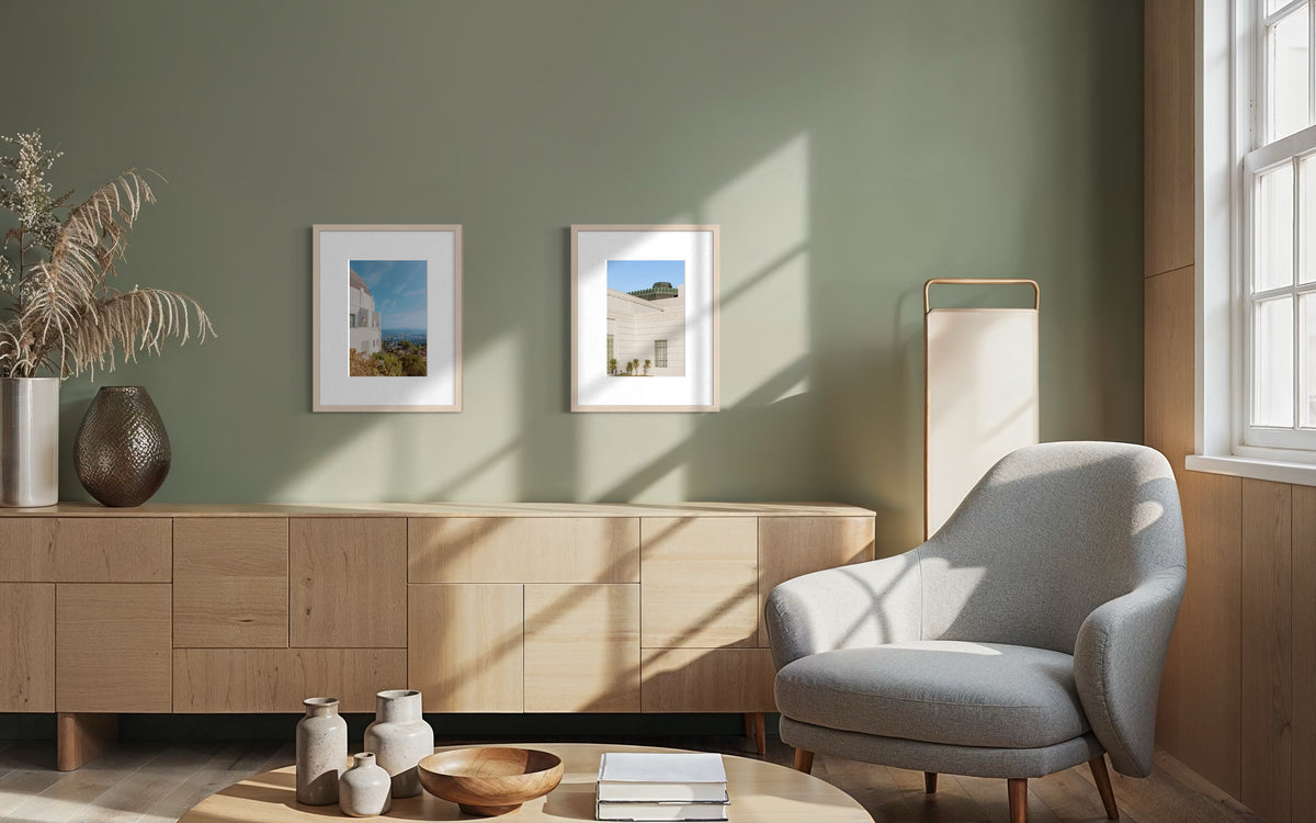 Griffith Observatory photograph on wall above grey chair and wood furniture in sunlit minimalist living room.
