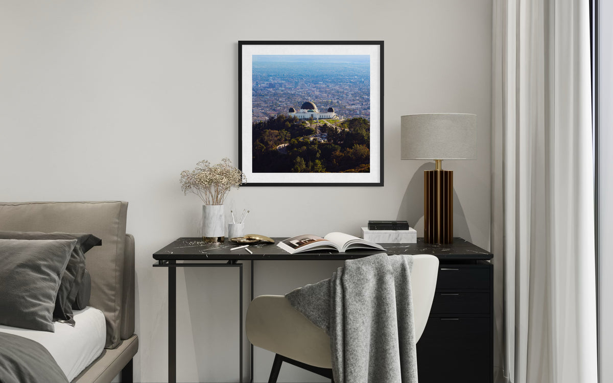 Open book and lamp on desk, Griffith Observatory photo above bed in a modern Los Angeles bedroom.