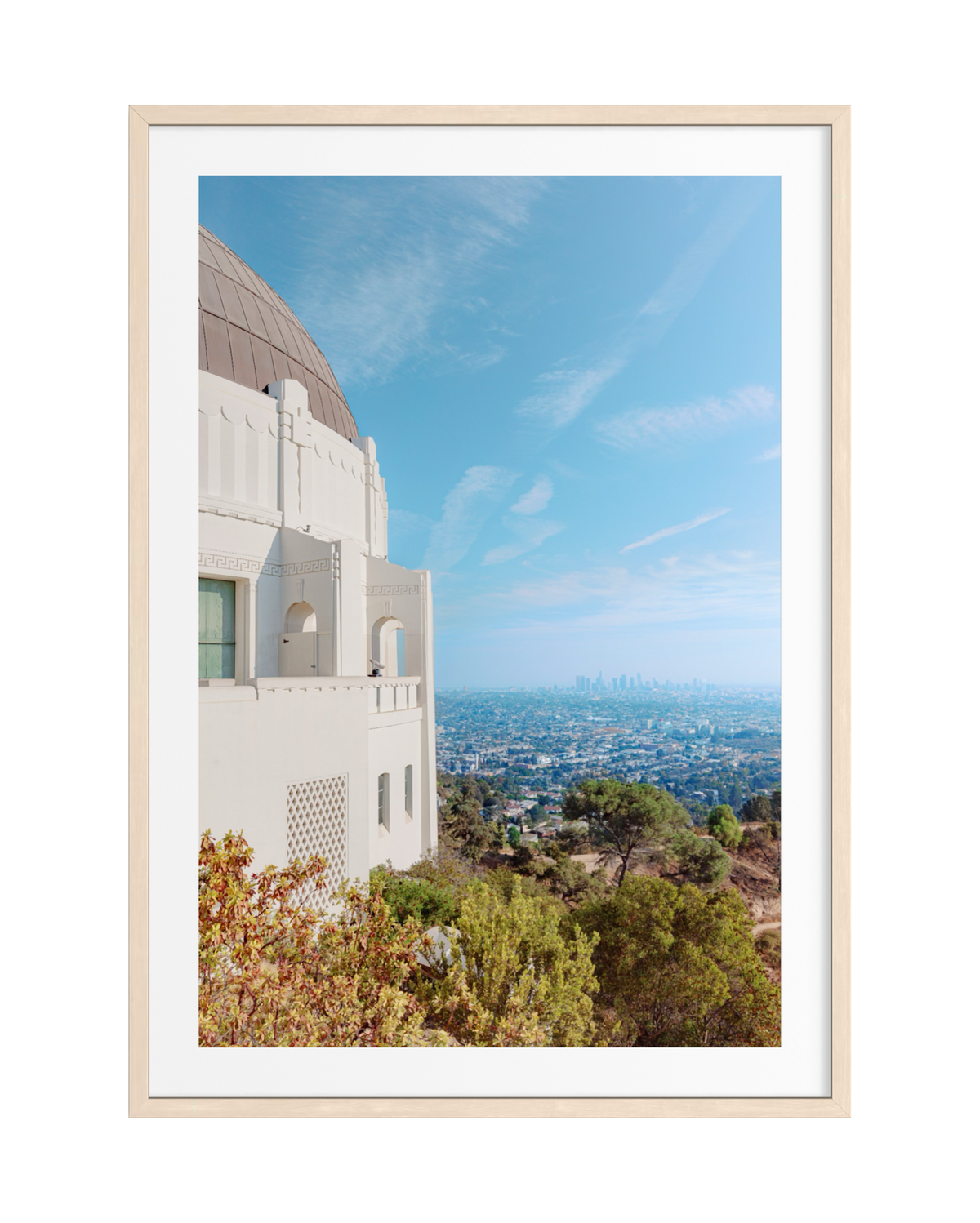 Downtown Los Angeles skyline seen from Griffith Observatory beneath a blue sky with scattered clouds.