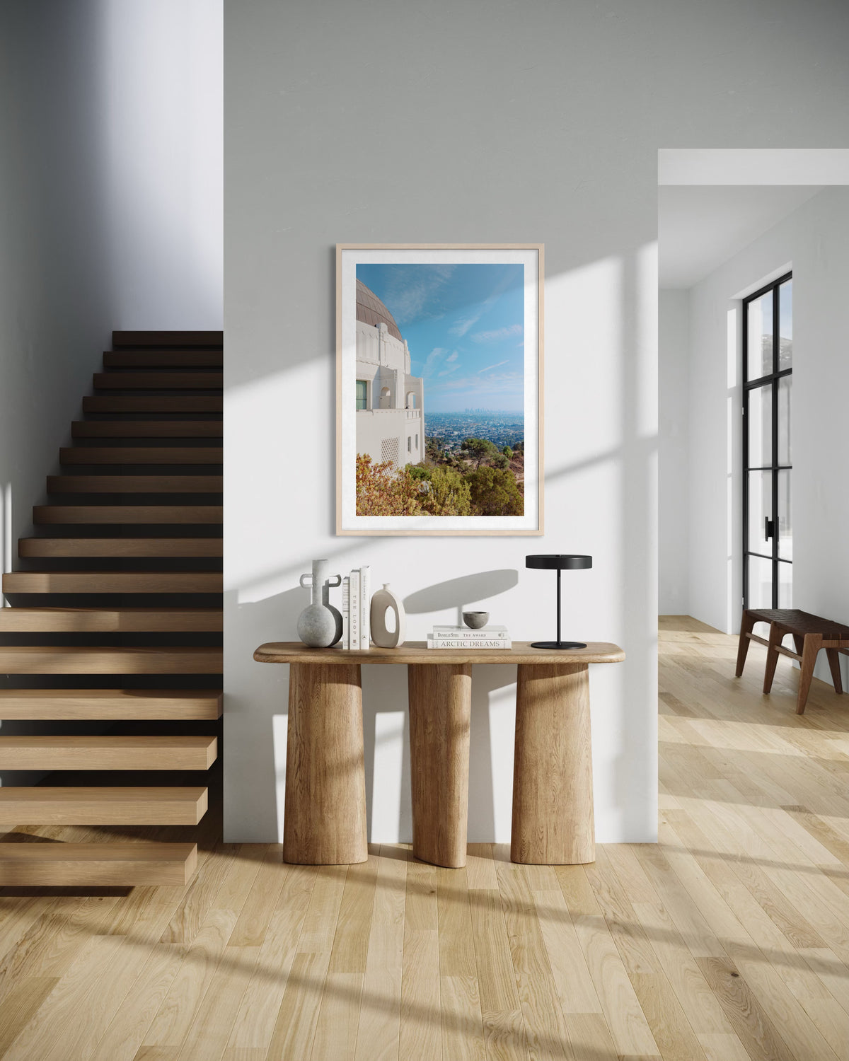 Downtown LA entryway with a wooden console, sunlight, wall art, and Griffith Observatory view in the background.