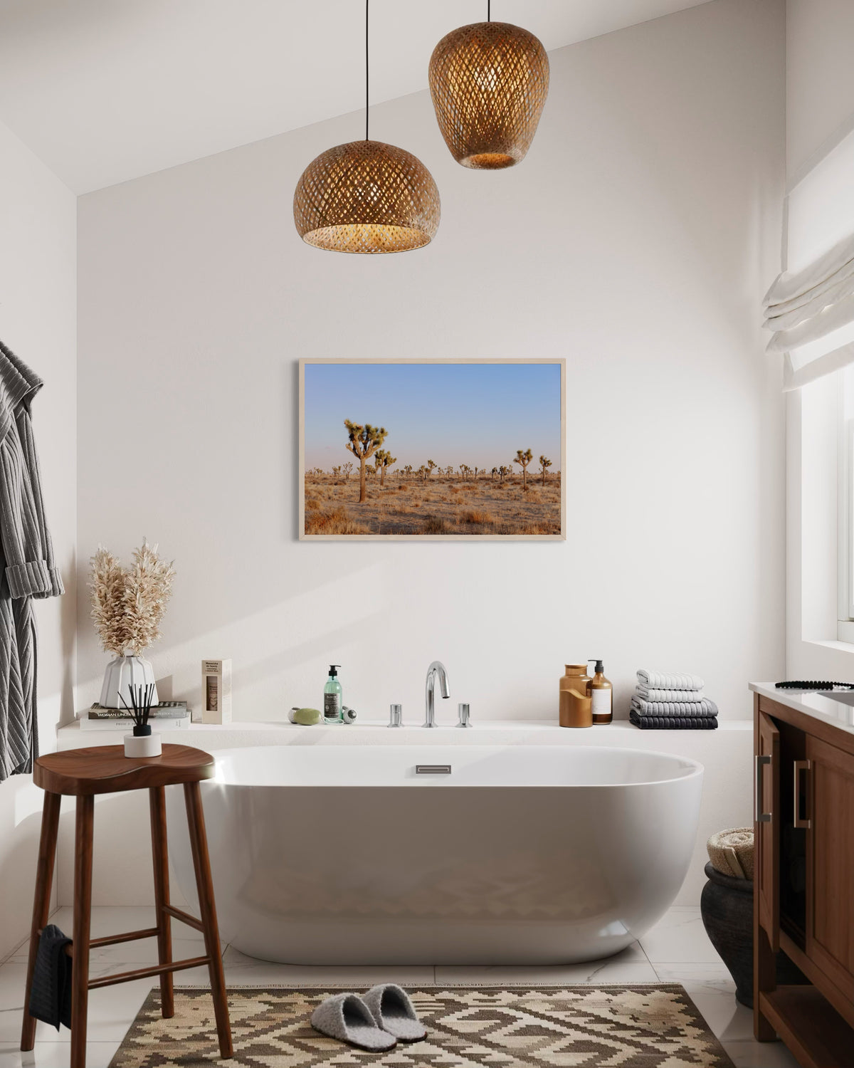Freestanding tub, wood stool, and “Joshua Tree Evening” art print of Joshua trees at dusk in bathroom setting.
