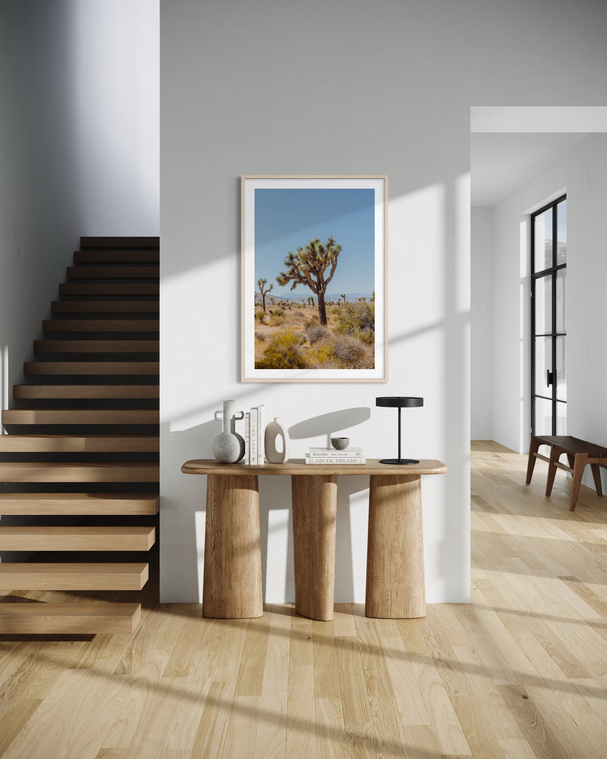 Framed Joshua Tree II print displayed above a wooden console table in a sunlit, modern entryway.