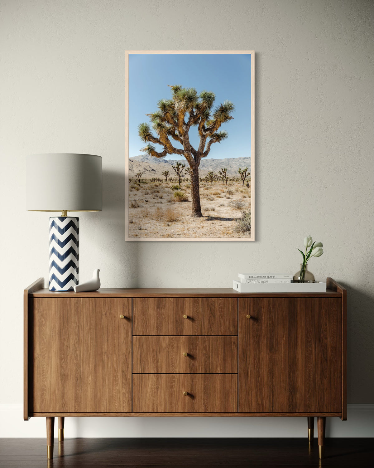 Framed Joshua Tree III photo above a mid-century cabinet with decor on a beige wall.