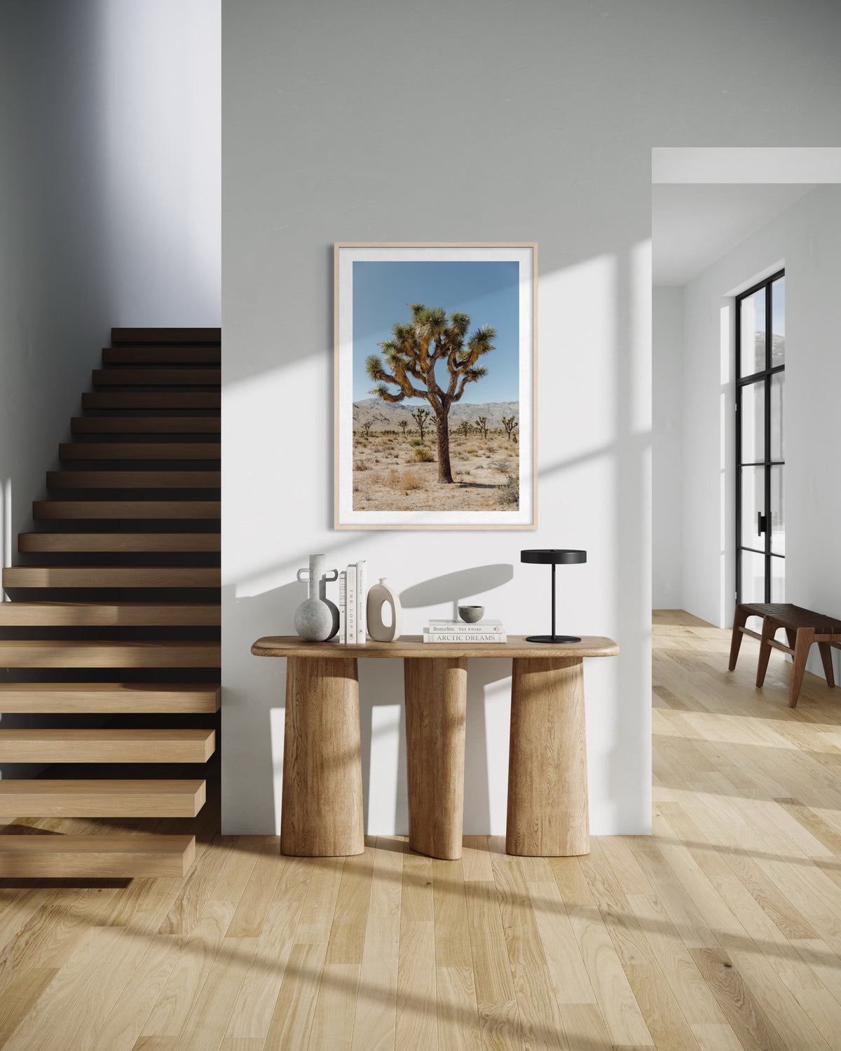 Framed Joshua Tree III print displayed above a wooden table; stairs and a bench visible in the background.