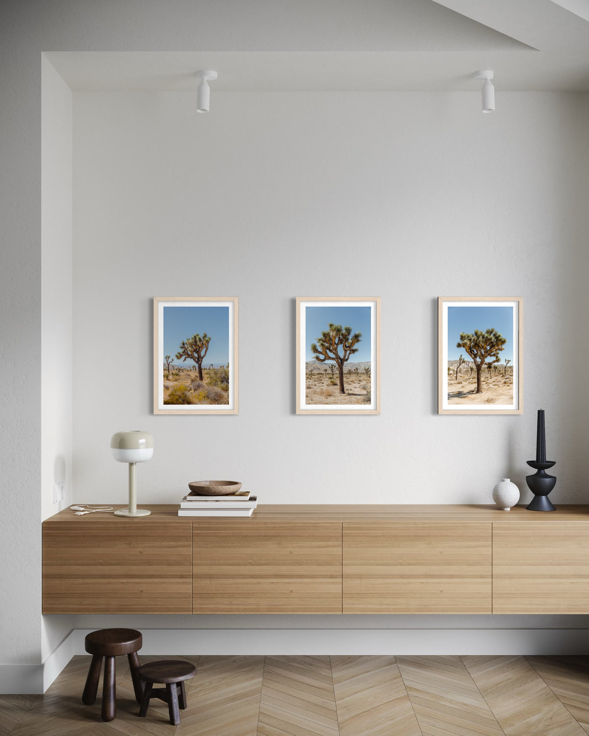 Black-and-white Joshua Tree landscape photograph displayed above a wooden sideboard against a white wall.