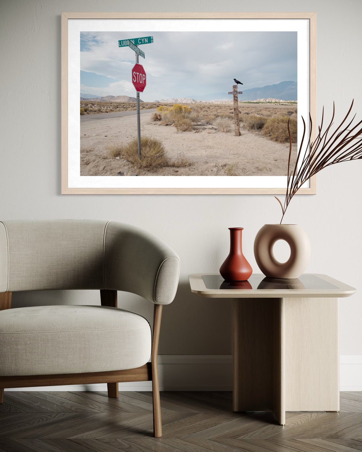 Framed print of a stop sign in Lone Pine’s high desert, displayed above a beige chair and table with two vases.