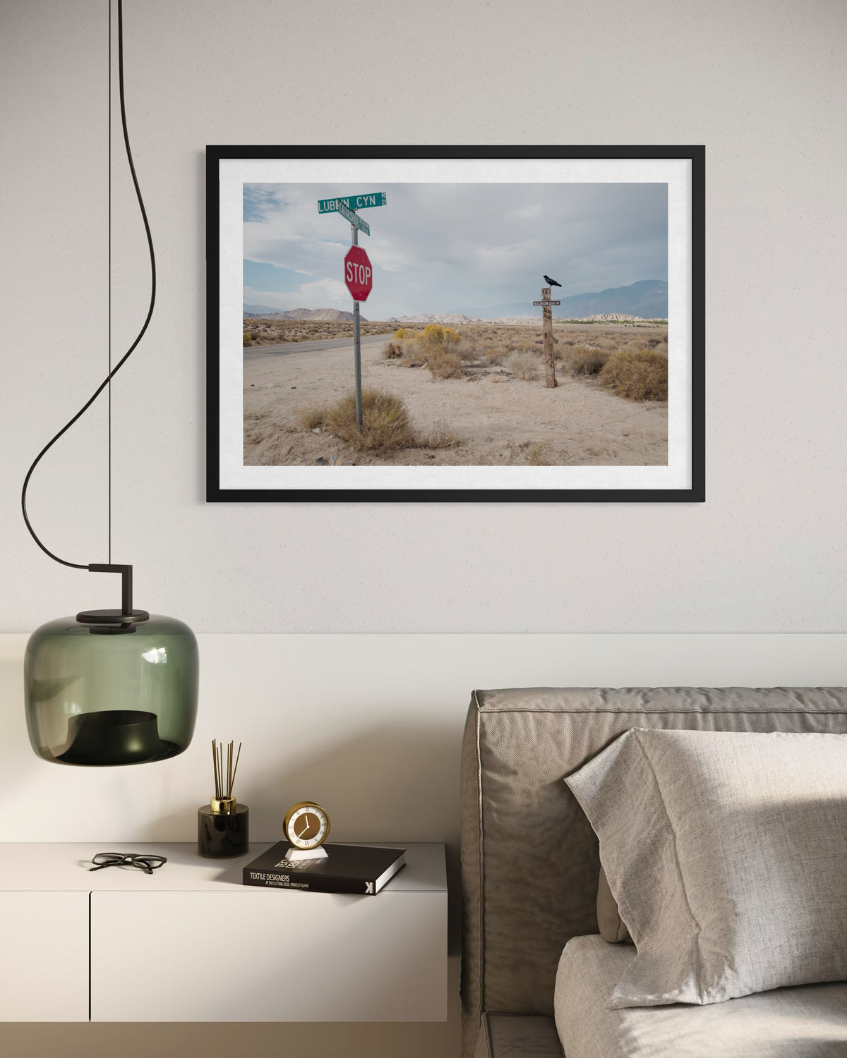 Framed photograph of Lone Pine, California pine tree hangs above contemporary bed with books and lamp.