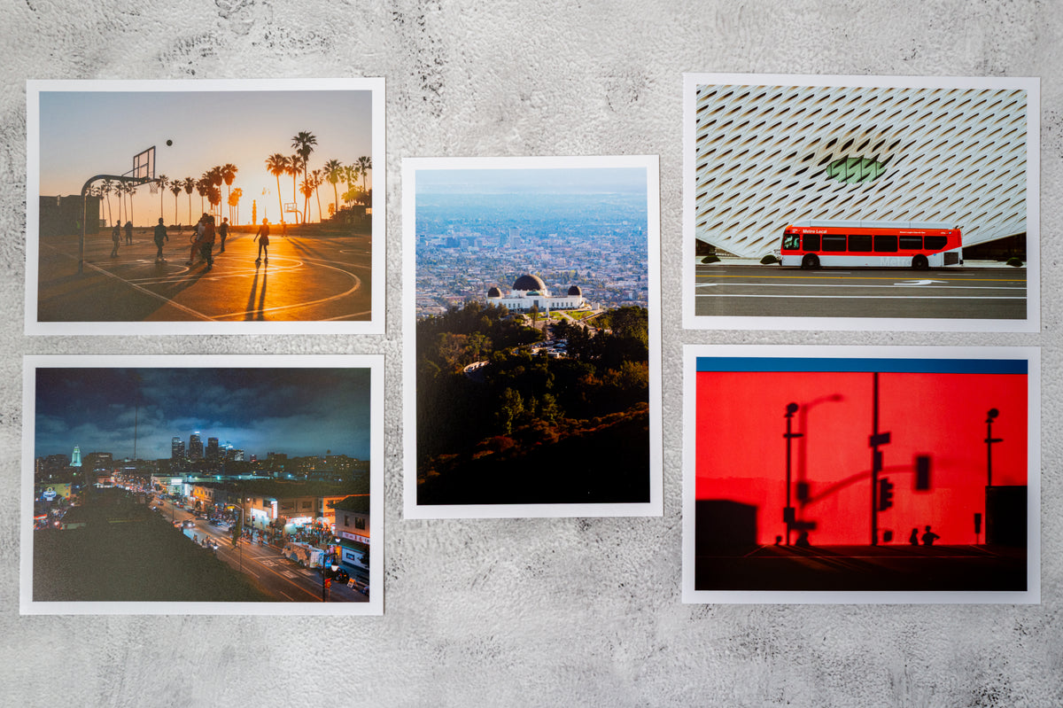 Five Los Angeles prints: basketball court, city skyline, Griffith Observatory, city bus, and red traffic lights.