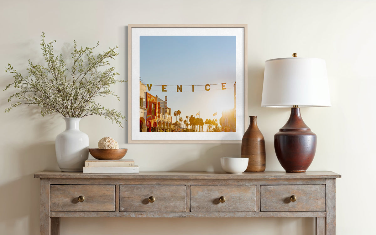 Venice street lamp glows in soft sunset light, canal and historic buildings visible in the background.