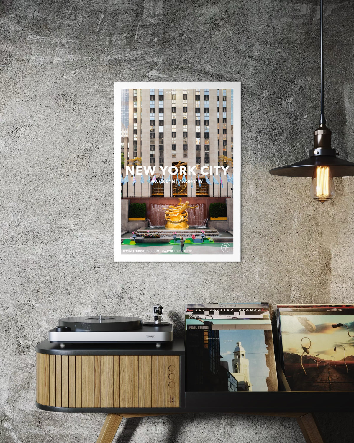 Framed NYC Poster No. 02 hangs above a record player on a wooden console against a light wall.