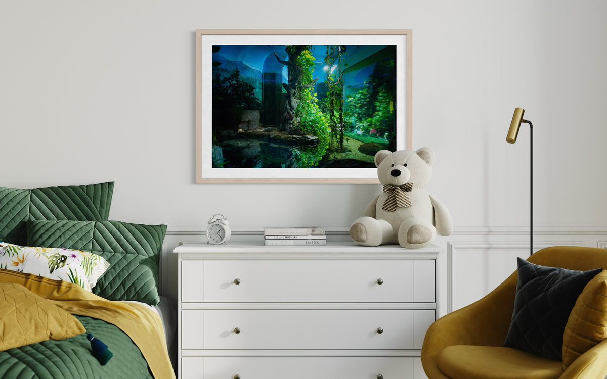 Green bed and olive chair beside white dresser with bear, books, and “Night at the Zoo” photo framed above.