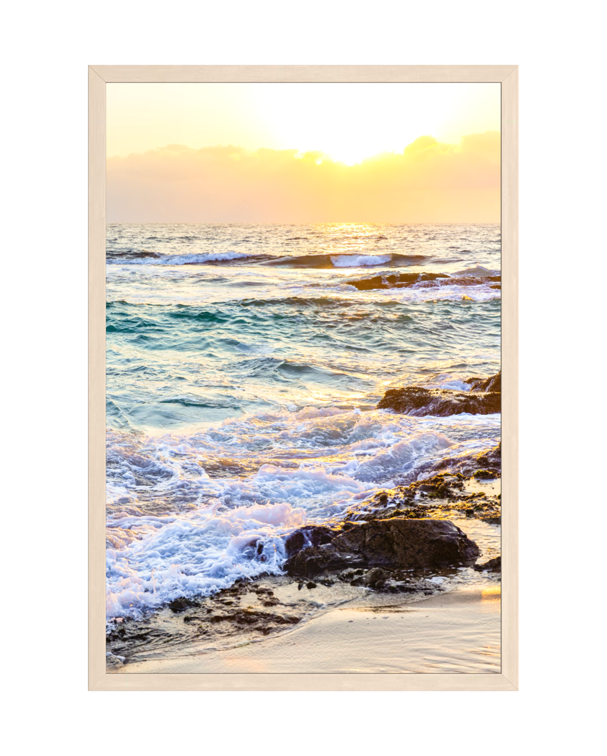Waves crash over rocks at sunset, with golden light reflecting on the water and sand.