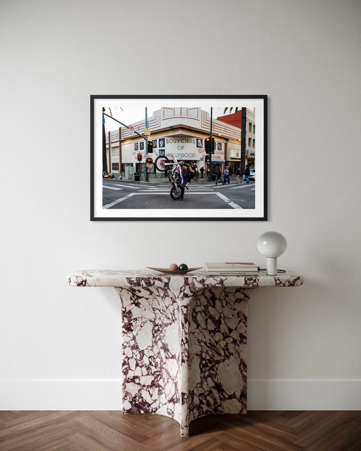 Motorcycle stunt rider performs on a Hollywood street, captured in a framed photography print.