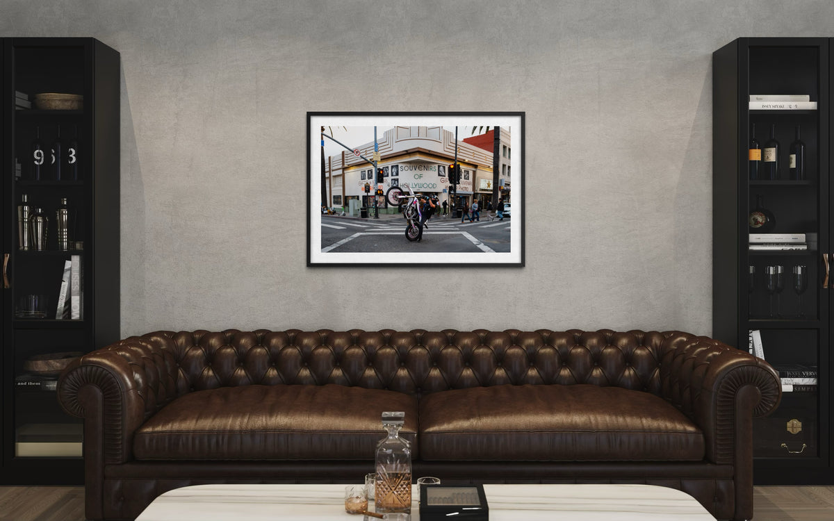Only in Hollywood“ Los Angeles cityscape photograph print in a black frame, displayed above a brown leather sofa.