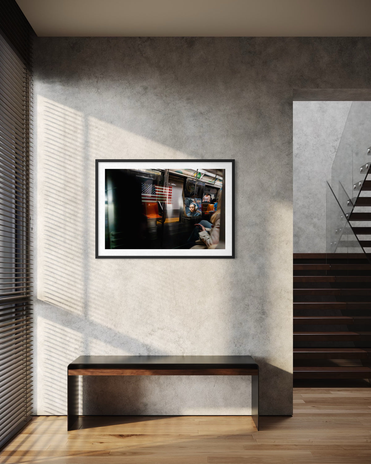 Black and white framed photo of a passing train in New York City, displayed above a bench on a concrete wall.