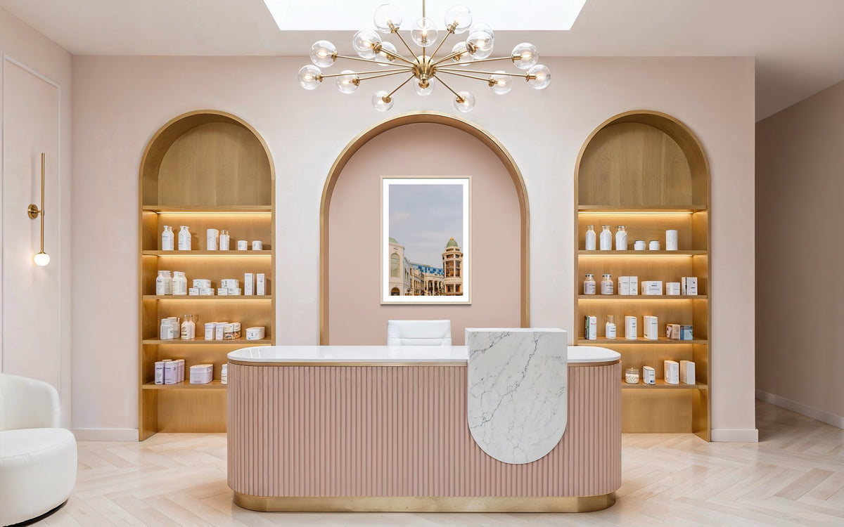 Marble reception desk, beauty shelves, and gold chandelier in a pastel-toned Beverly Hills interior.