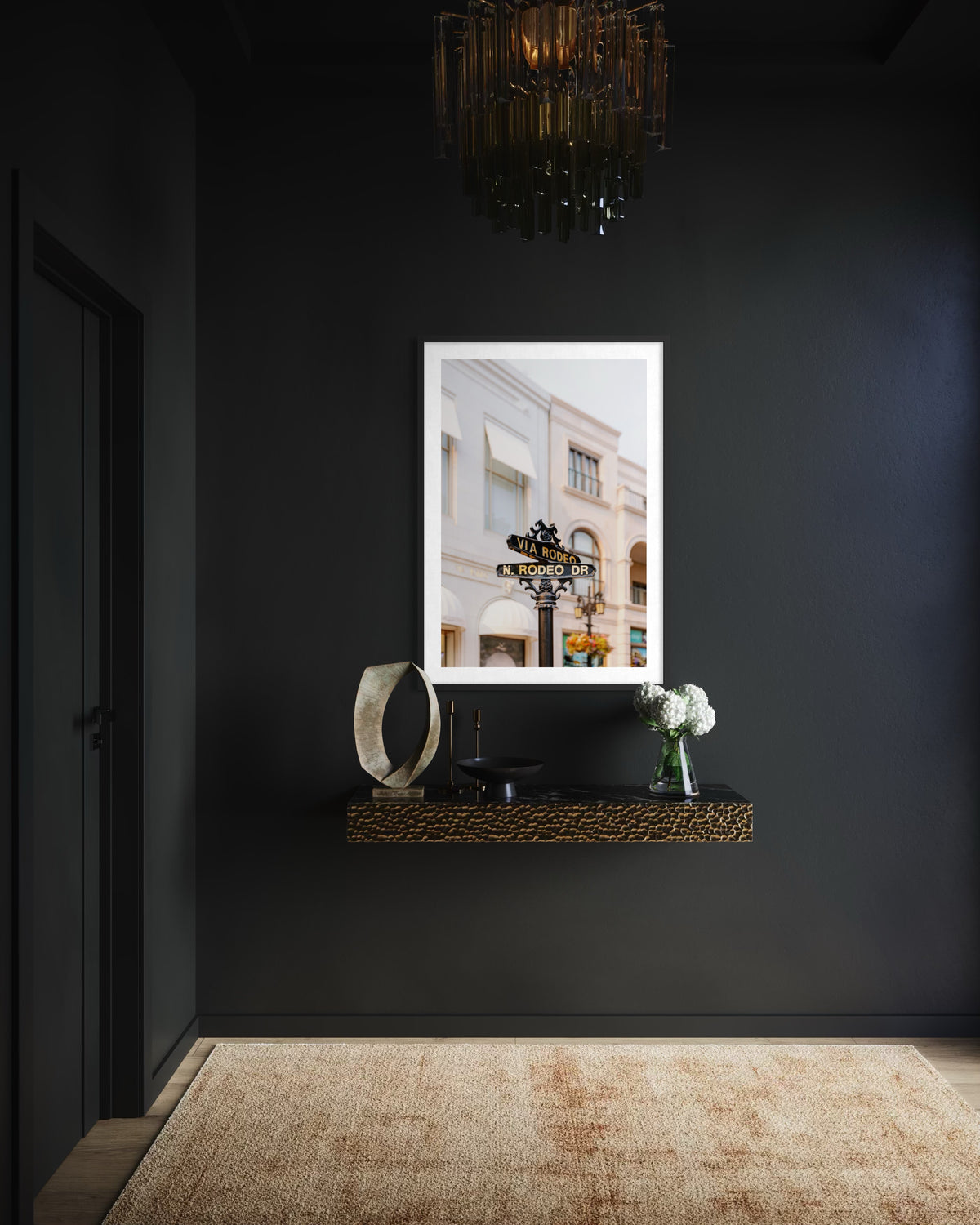 Rodeo Drive street sign displayed on a floating shelf against a dark wall, photographed in Beverly Hills.