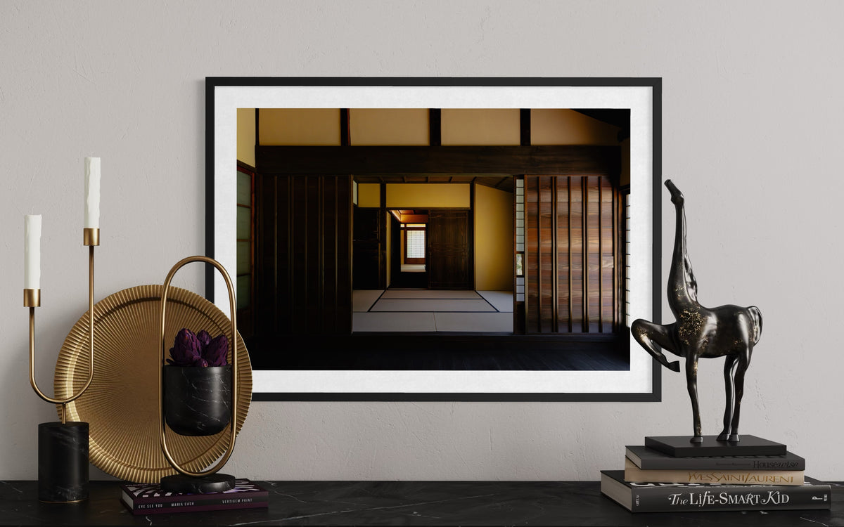 Framed “Shōya House Interior” photo on shelf with decor, warm lighting, candle holders, and giraffe sculpture.