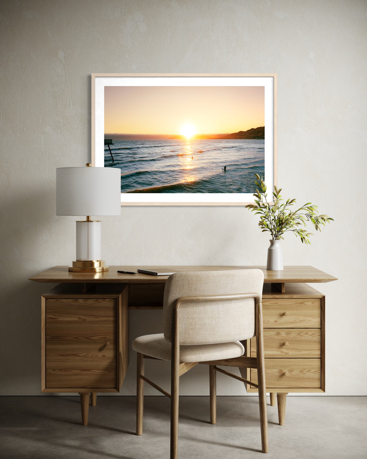 Wood desk with lamp, chair, plant, and framed Surfers at Sunset print displayed in a minimalist room.