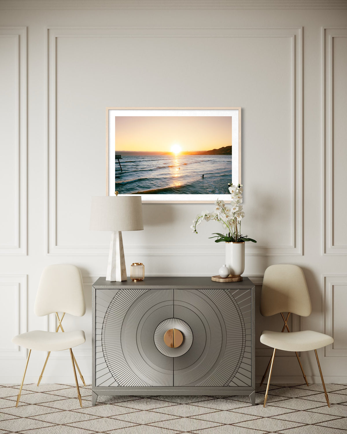 Two chairs, lamp, and orchid in a modern room with Surfers at Sunset photo art of the Pacific coast on the wall.
