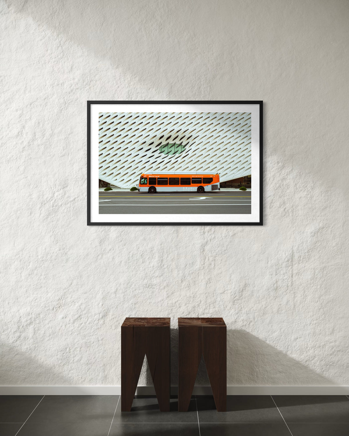 LA metro bus artwork displayed above two dark stools on tiled floor, photographed near The Broad in Los Angeles.