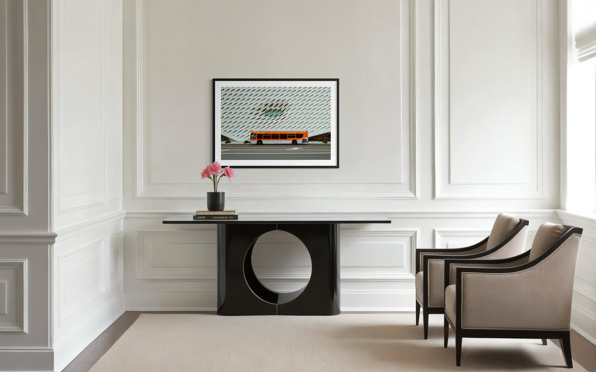Los Angeles room with beige chairs, black console, pink flowers, and framed Metro bus art near The Broad.