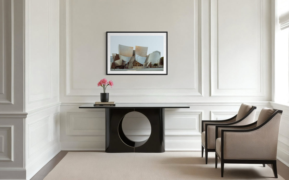 Beige chairs, black table, pink flowers, and framed art of Walt Disney Concert Hall in a modern Los Angeles room.